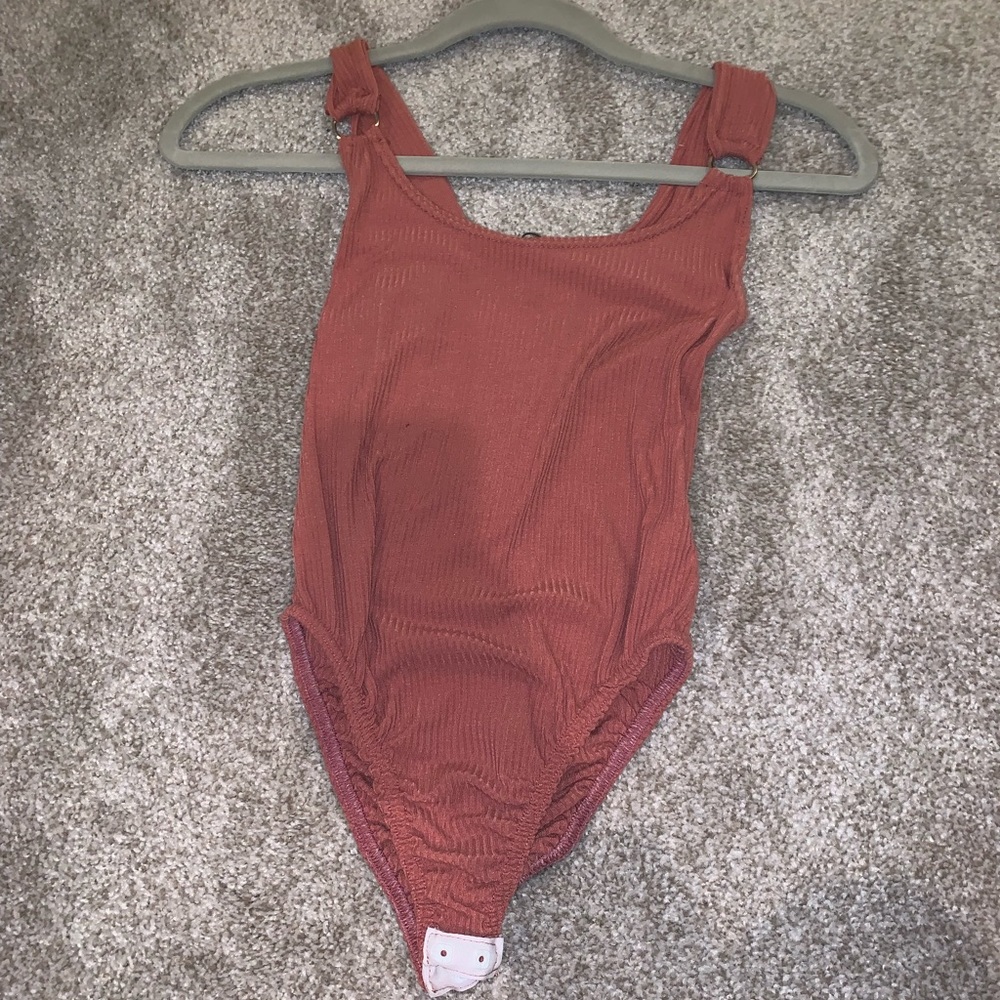 Rust color bodysuit with silver rings on straps